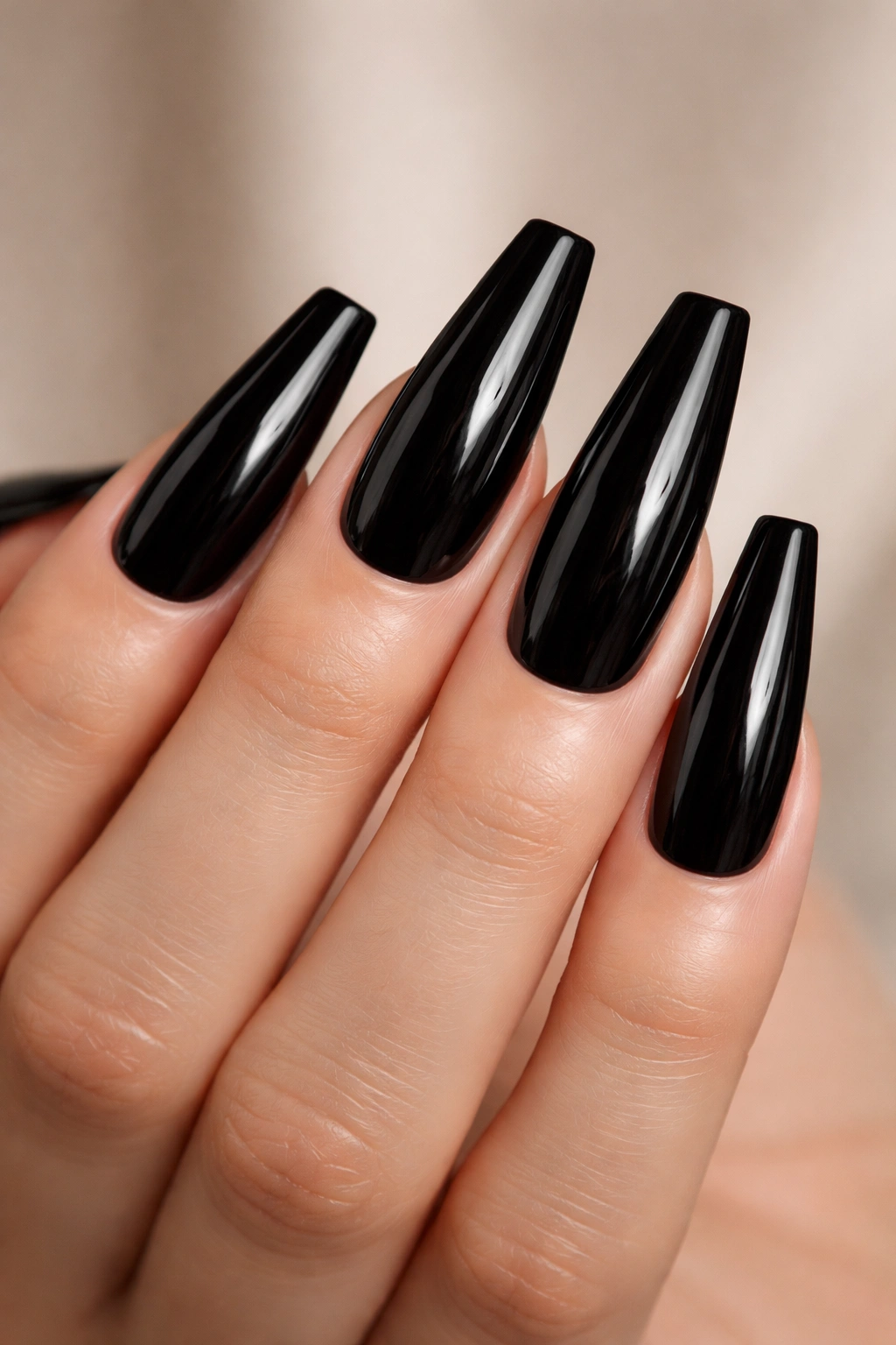 Bare hand showing jet-black coffin nails with a glassy mirror finish.