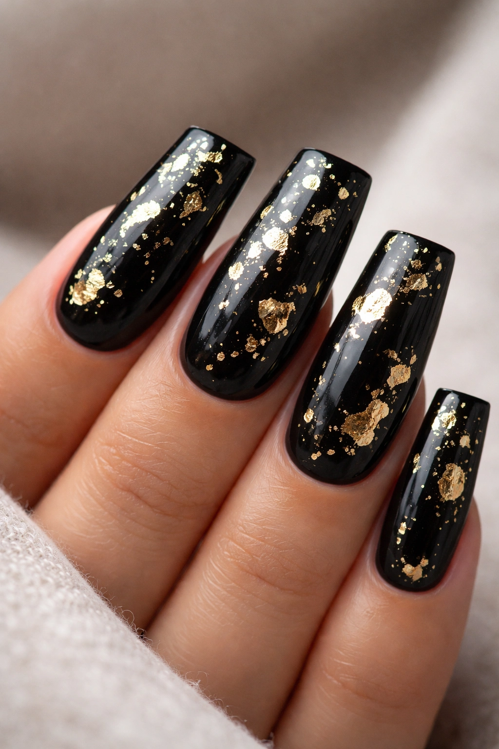 Jet-black nails with scattered gold leaf flakes