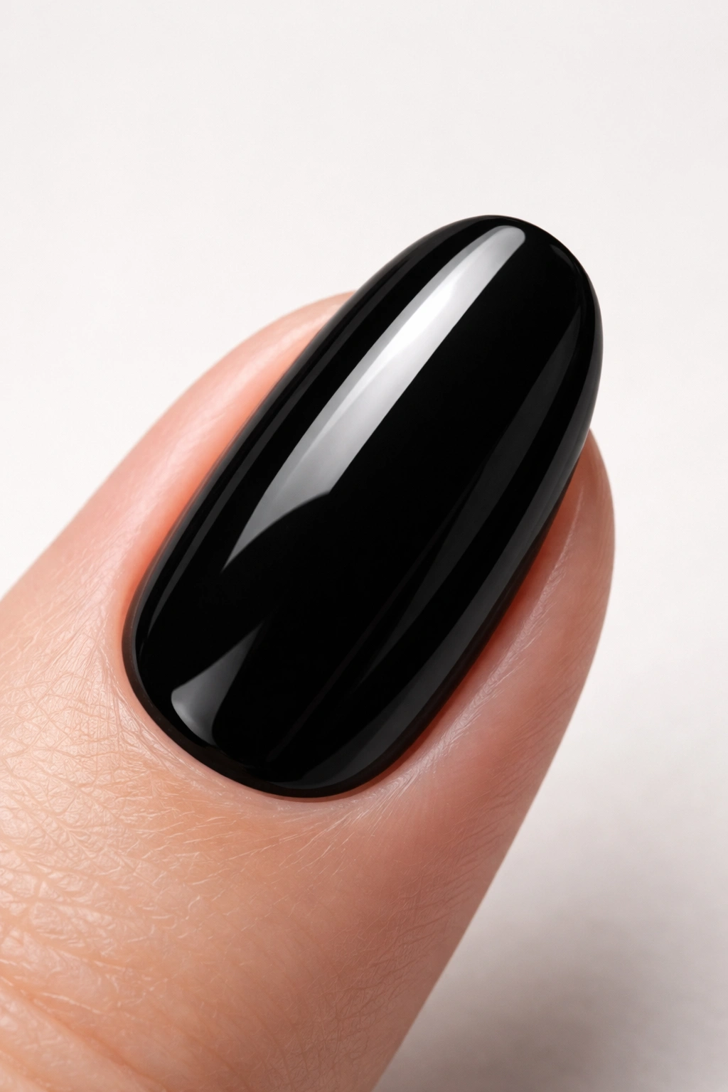 Close-up of a fingernail painted in glossy black polish against a neutral background