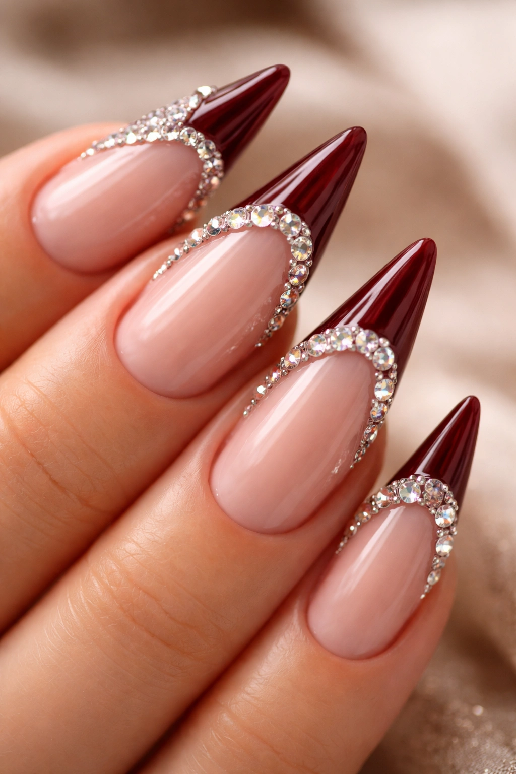Close-up of dark red nails with jeweled accents on the tip edge