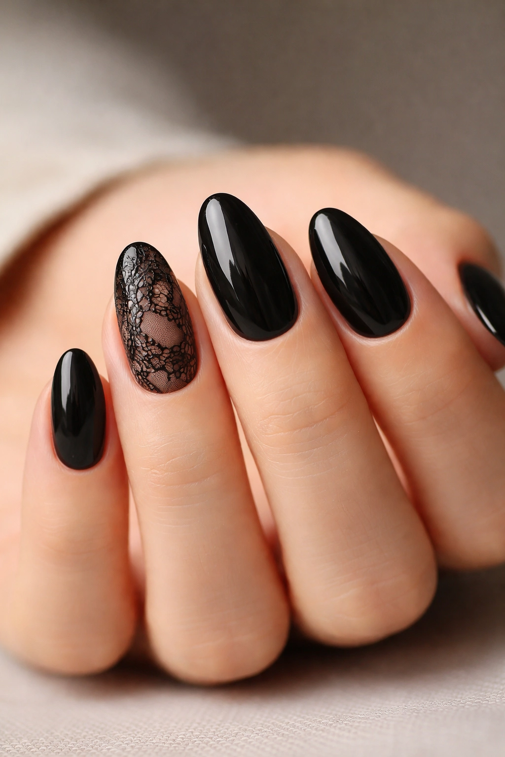 Close-up of short black almond nails with lace-inspired detailing on an accent nail.