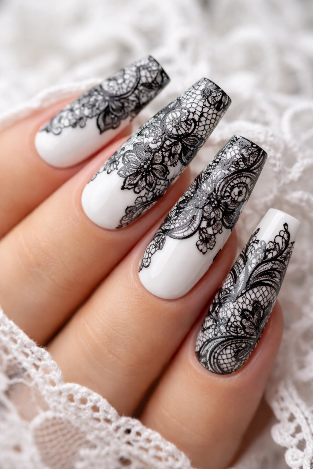 Close-up of coffin nails with black lace patterns on a white base