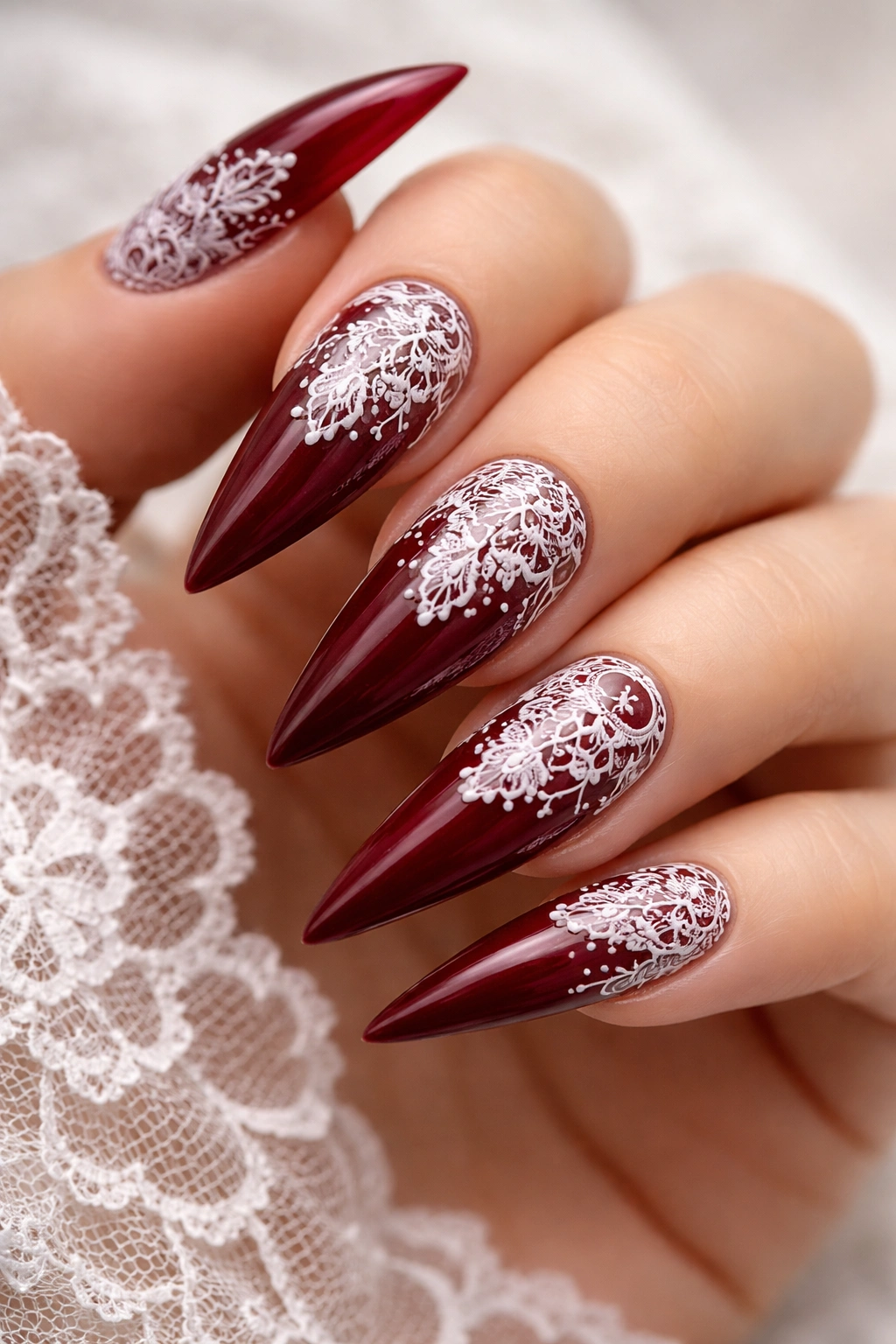 Dark red nails with delicate white lace patterns.