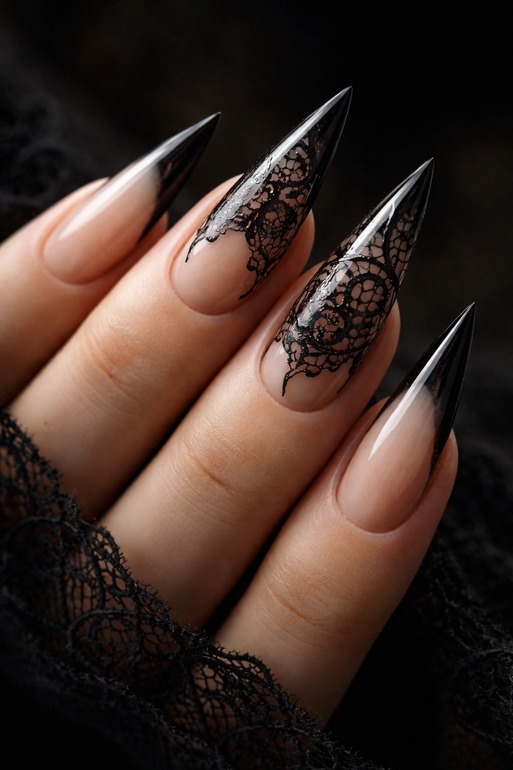 Close-up of sheer nude stiletto nails with black lace accents
