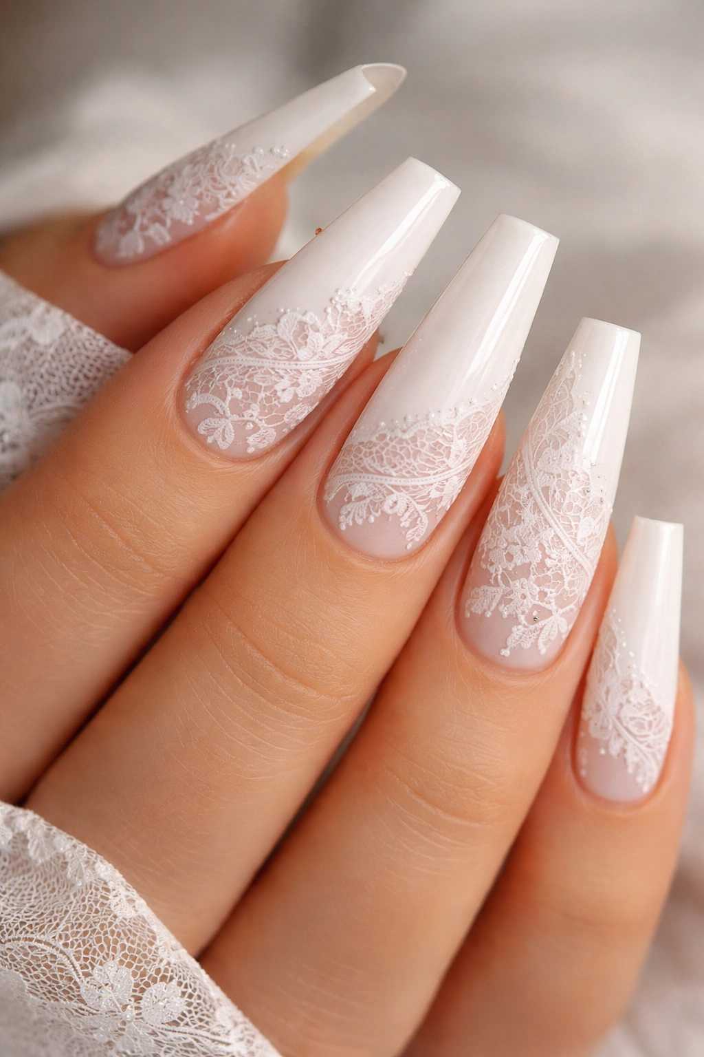 Close-up of white coffin nails featuring delicate lace-inspired patterns