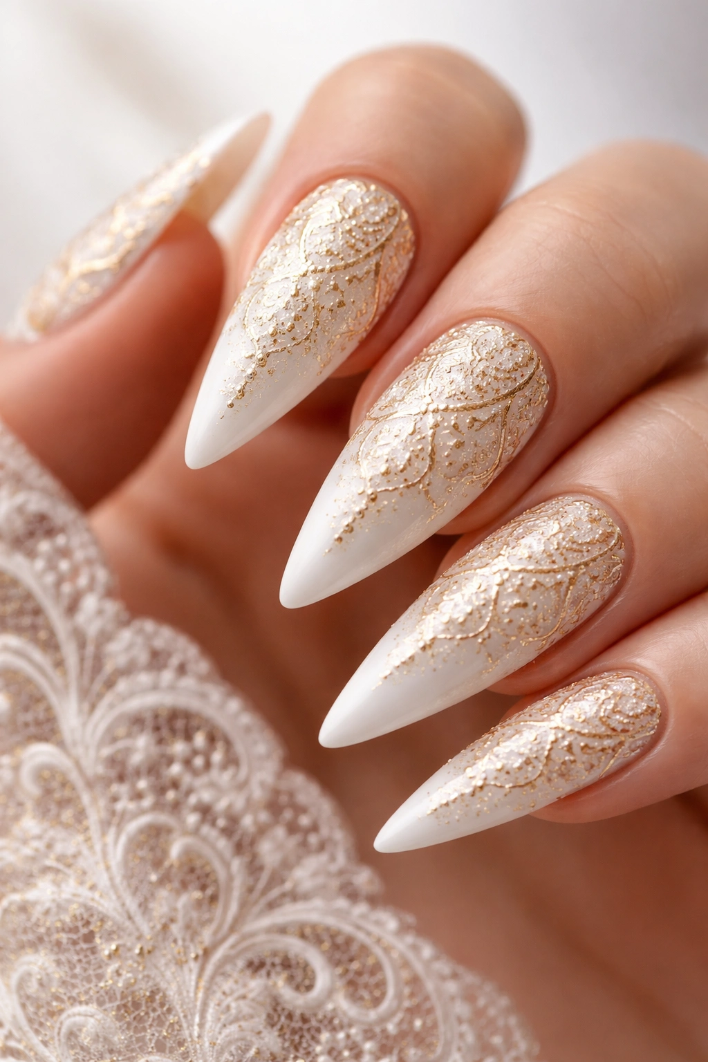 Close-up of white stiletto nails with delicate gold lace pattern