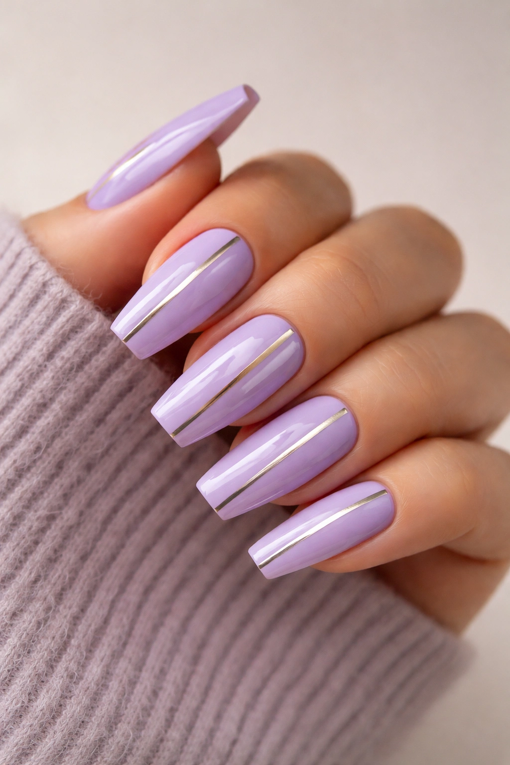 Close-up of lavender coffin nails with thin metallic striping tape creating clean lines