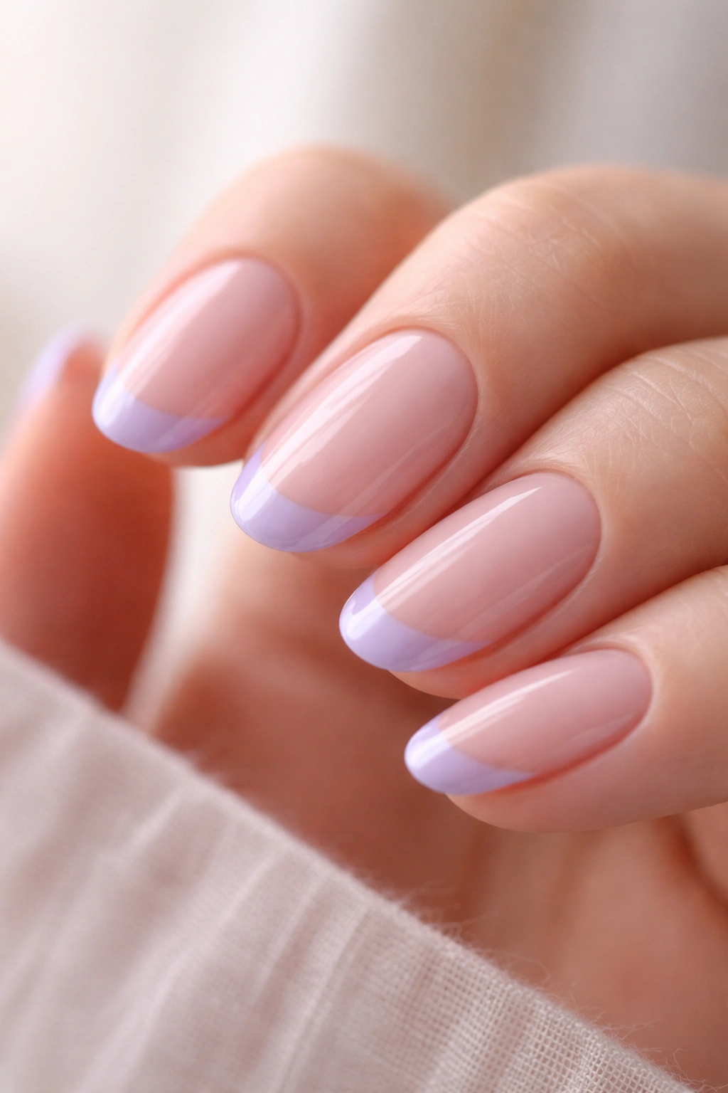 Close-up of short oval nails with lavender French tips on sheer pink base.
