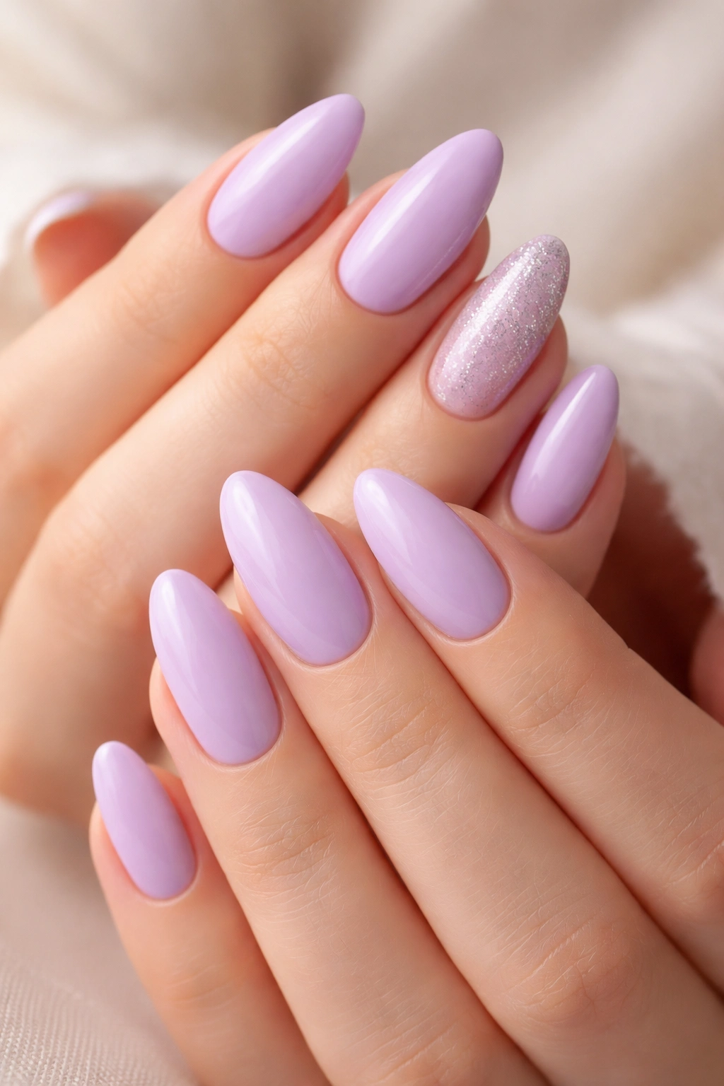 Close-up of lavender almond nails with a silver sparkle accent nail on a neutral background