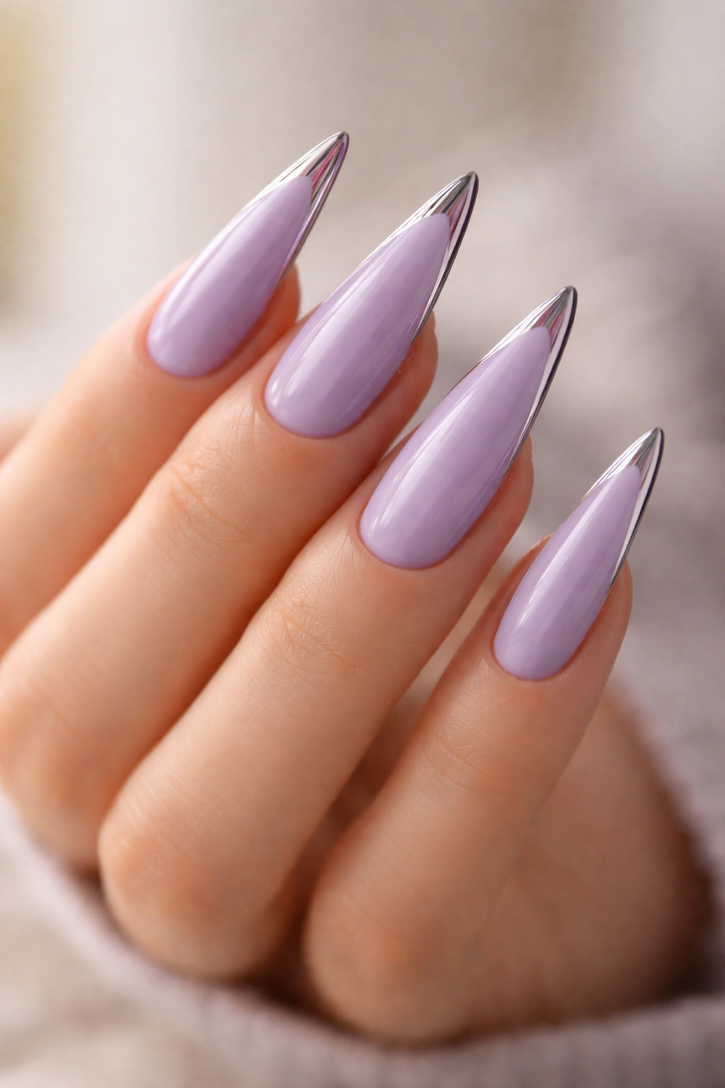 Close-up of lavender stiletto nails with chrome tip accents on a hand