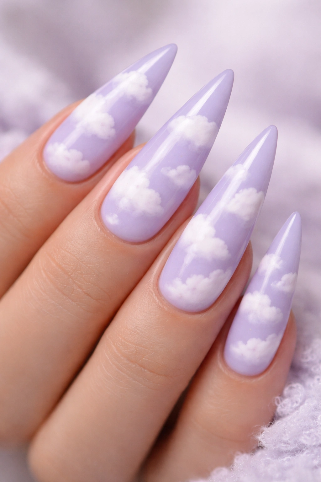 Close-up of pale lavender stiletto nails with fluffy white cloud patterns