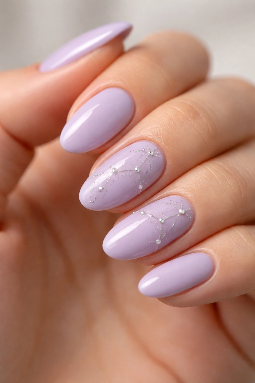 Close-up of soft lavender almond nails with fine silver constellation lines on accent nails
