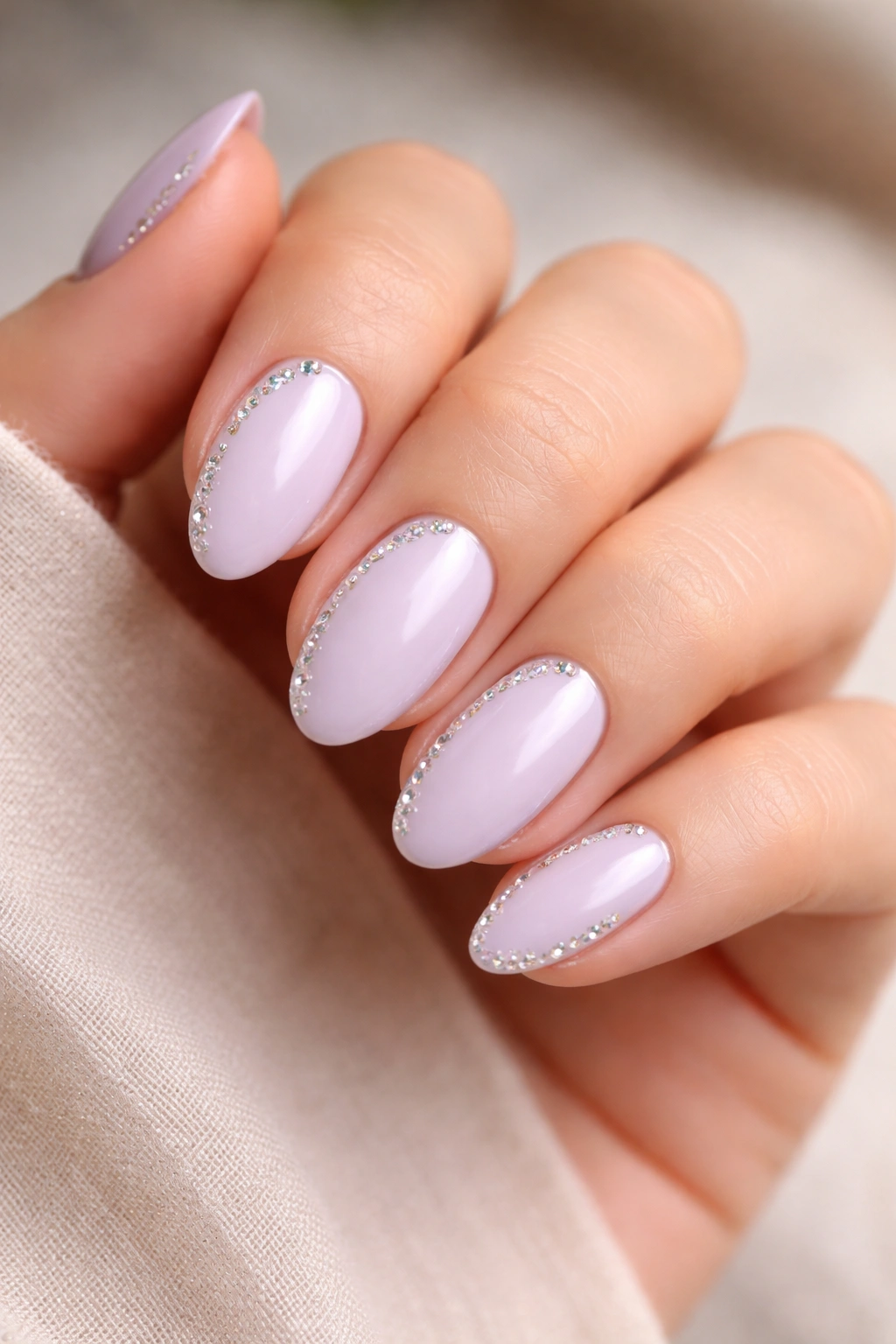 Close-up of pale lavender almond nails with clear crystal edge