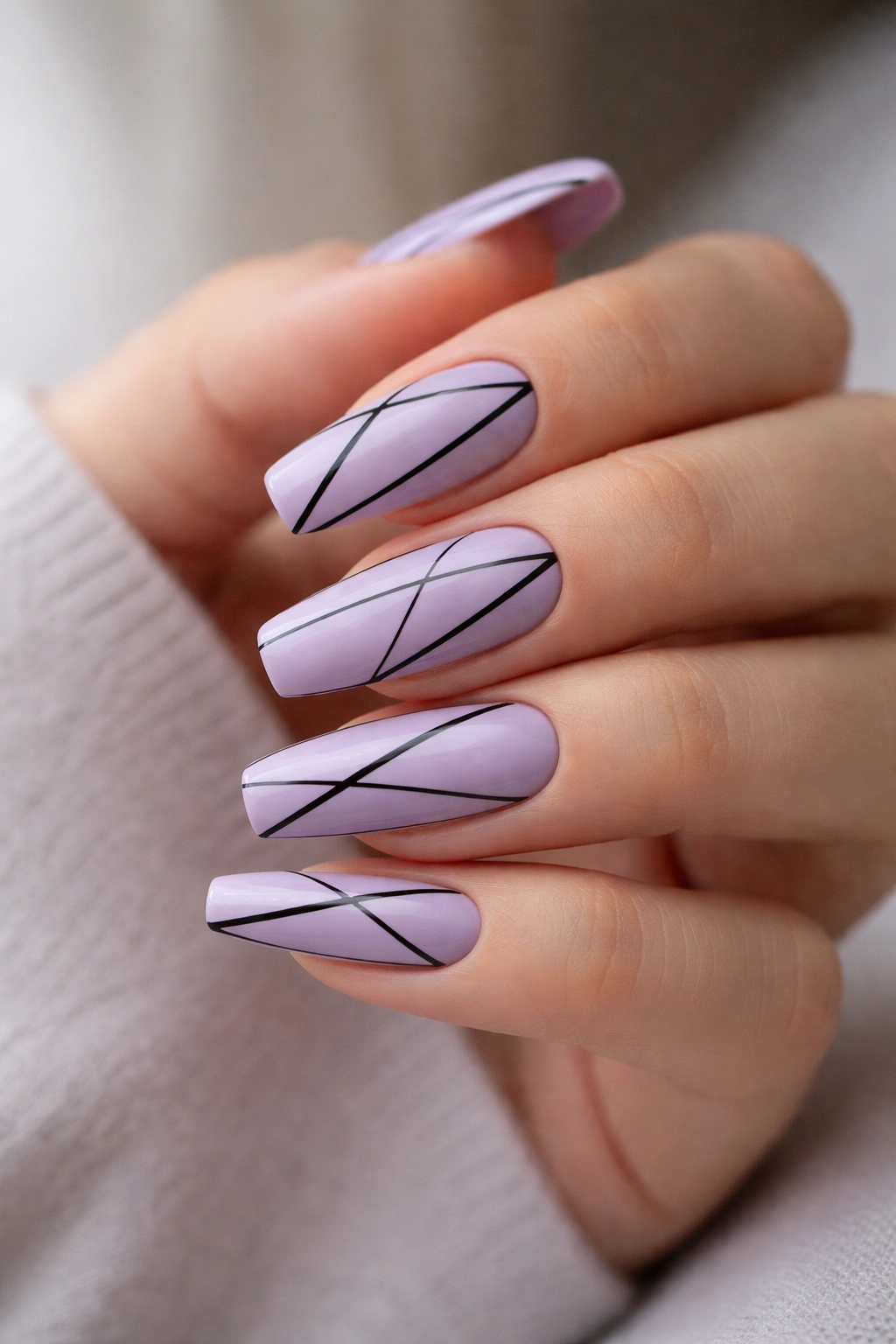 Close-up of lavender coffin nails with black geometric lines on a hand, glossy finish