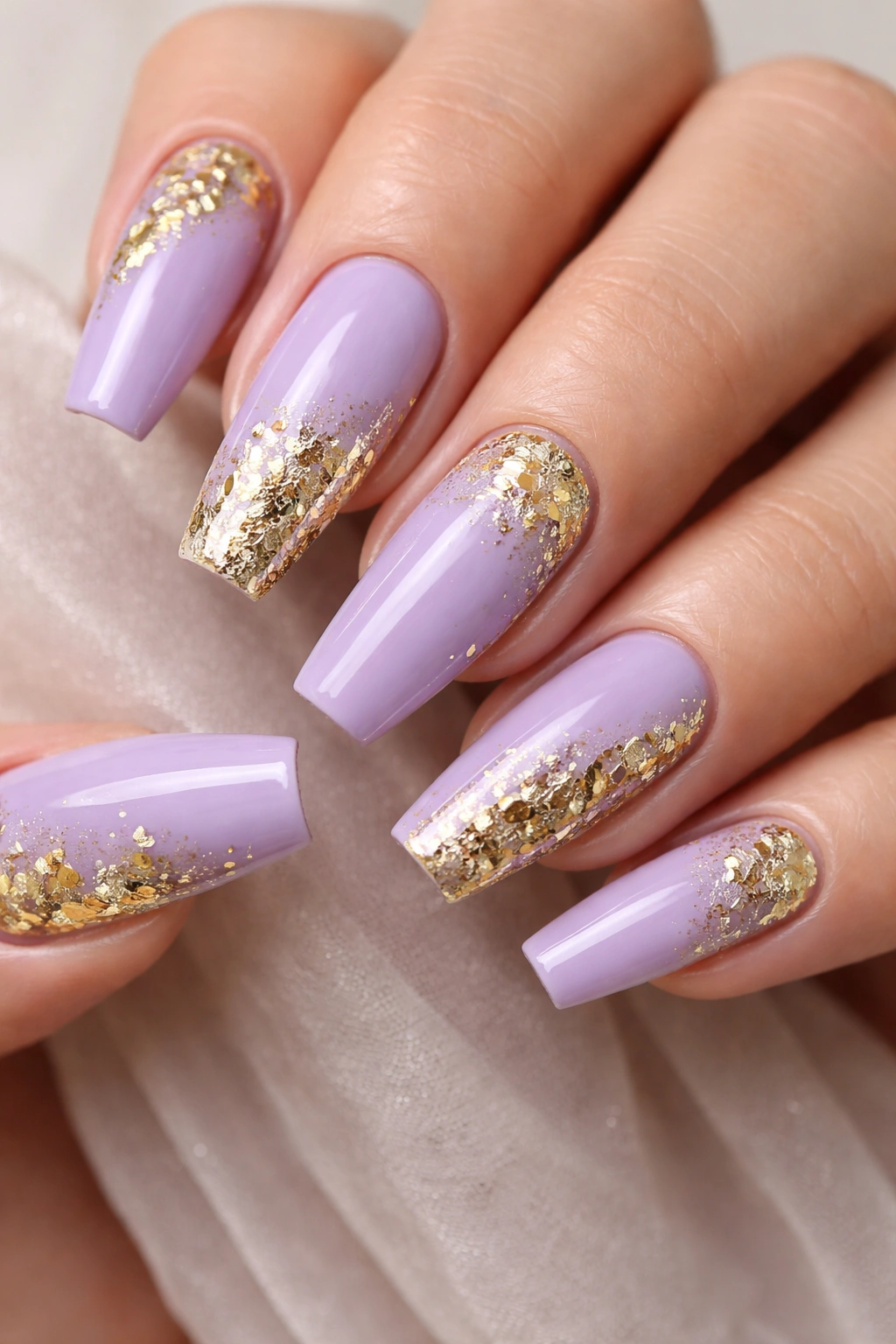 Close-up of lavender coffin nails with gold leaf accents on a neutral background