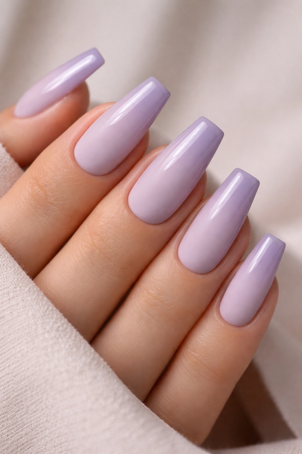 Close-up of coffin nails with matte lavender base and glossy tip gradient