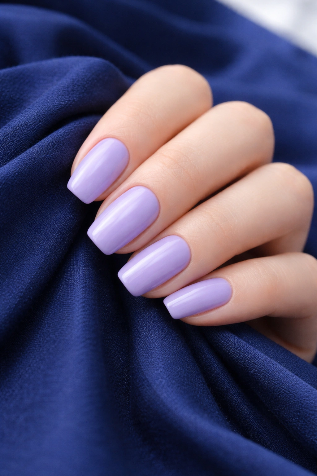 Lavender nails on navy fabric background