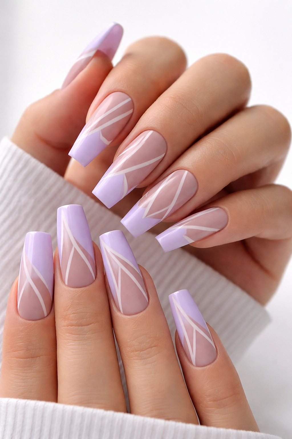 Close-up of lavender coffin nails with negative-space geometric patterns on nude base