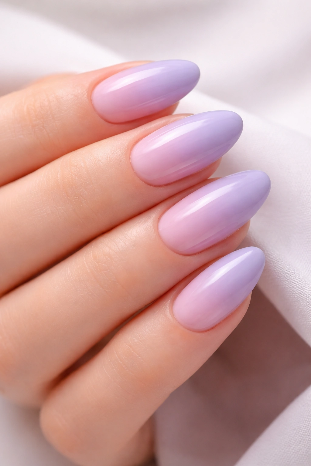 Close-up of lavender to blush pink ombre nails on a neutral background