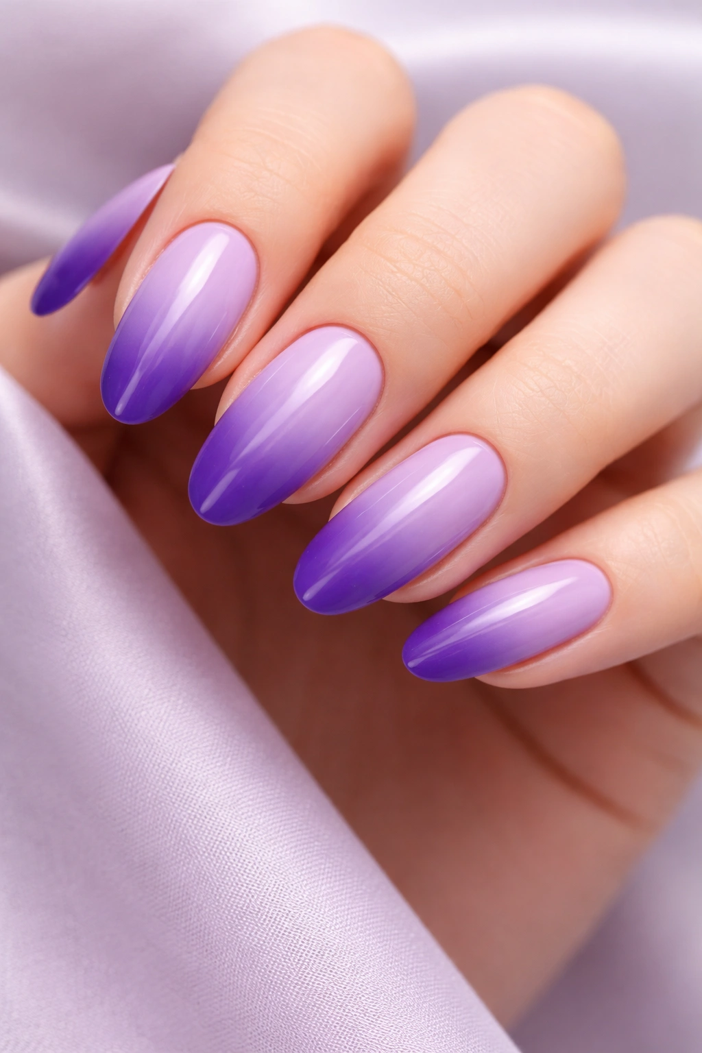 Close-up of lavender nails fading to purple tips in a seamless ombre.