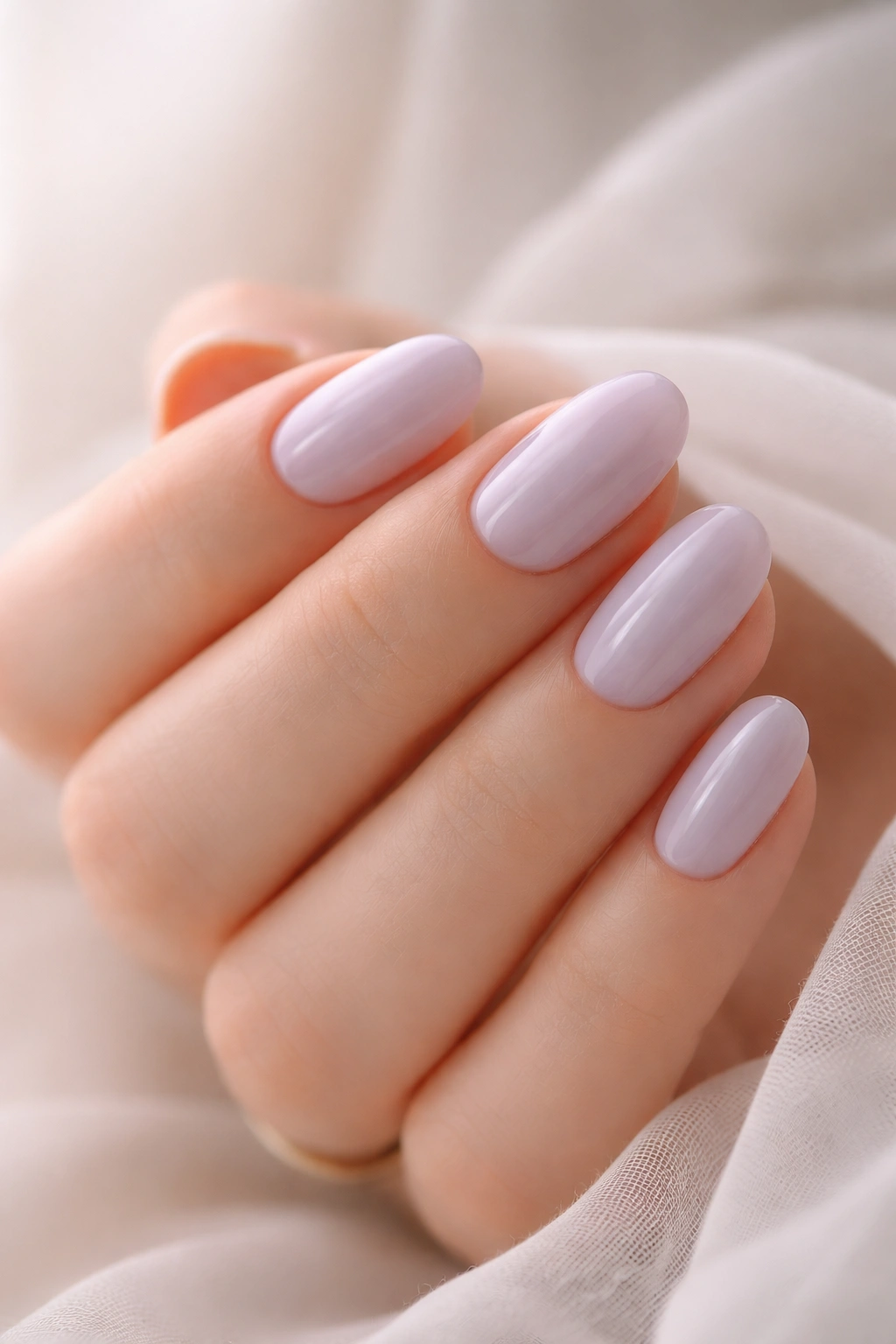 Close-up of short oval nails with sheer pale lavender polish