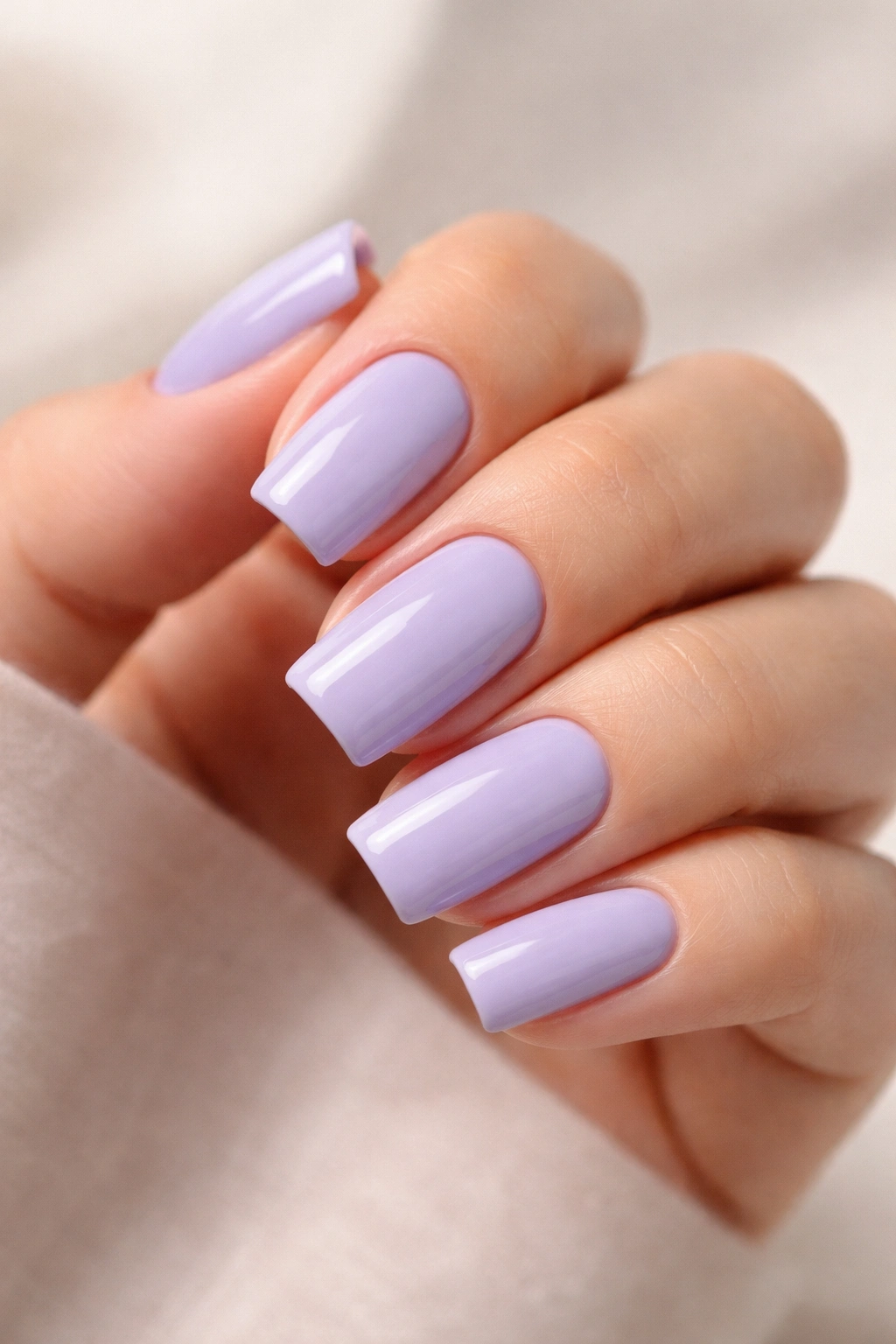 Close-up of lavender soft square nails on a neutral background