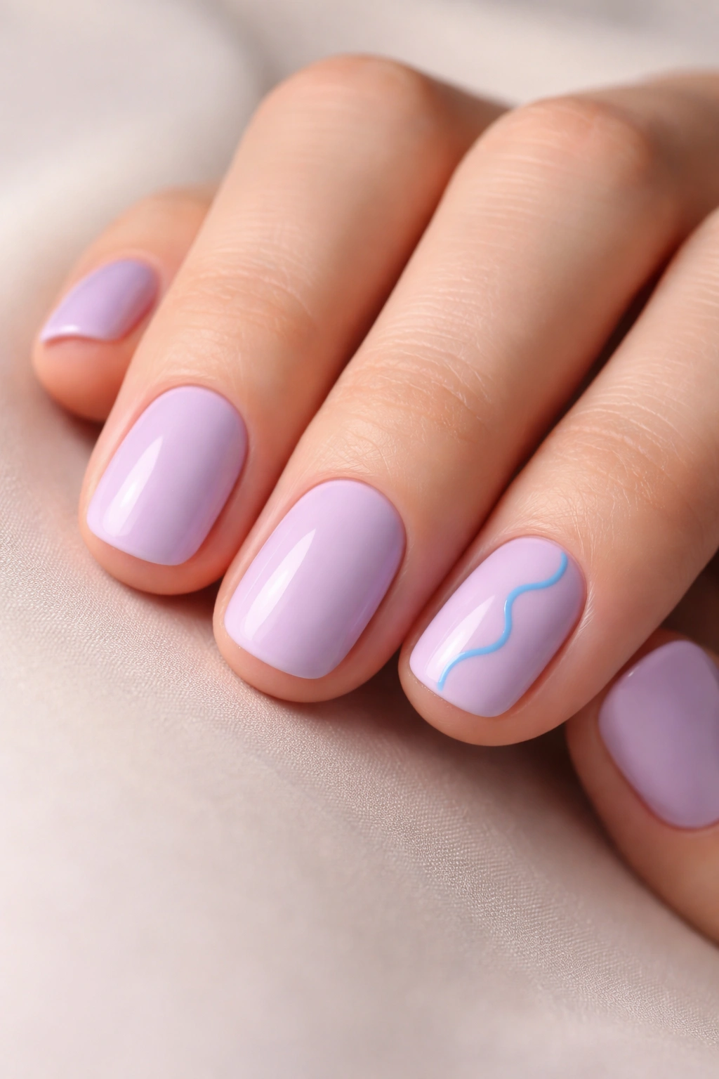 Close-up of soft lavender nails with blue squiggle accent