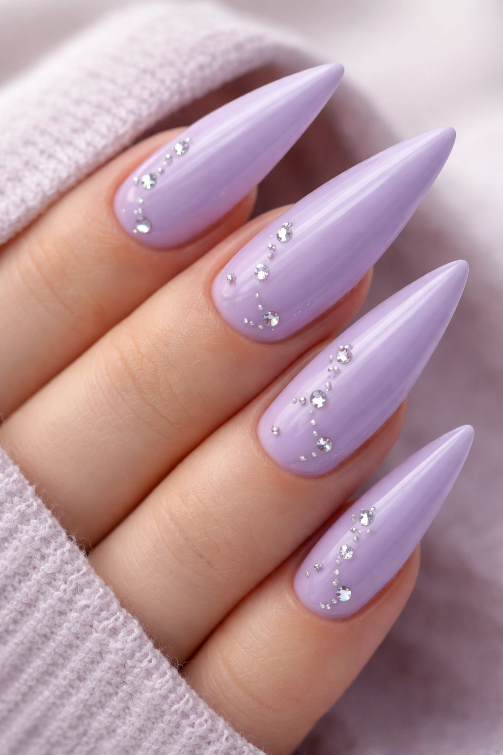 Lavender pastel stiletto nails with scattered rhinestones close-up