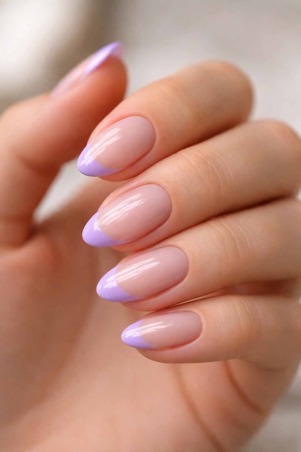 Close-up of short almond nails with lavender French tips on a bare hand