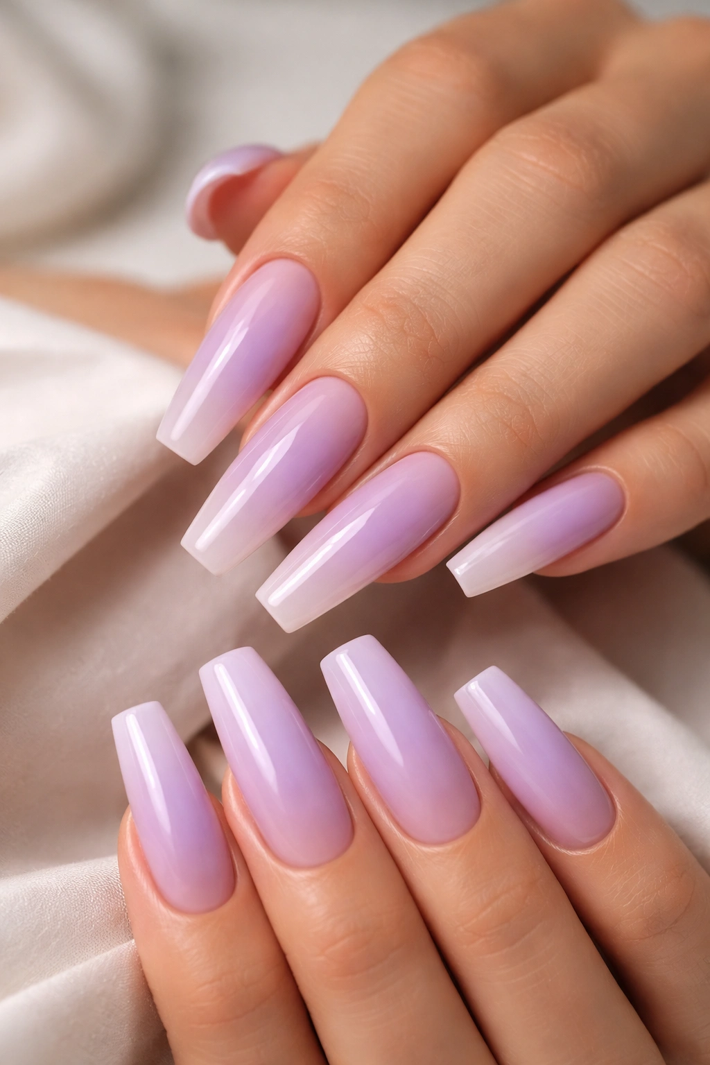 Close-up of lavender coffin nails fading to translucent tips revealing nude base.