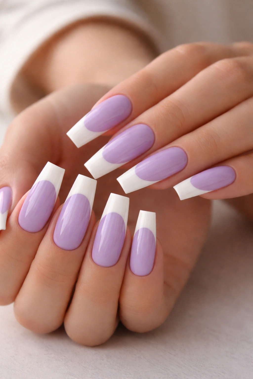 Close-up of lavender coffin nails with white tips in a studio setting