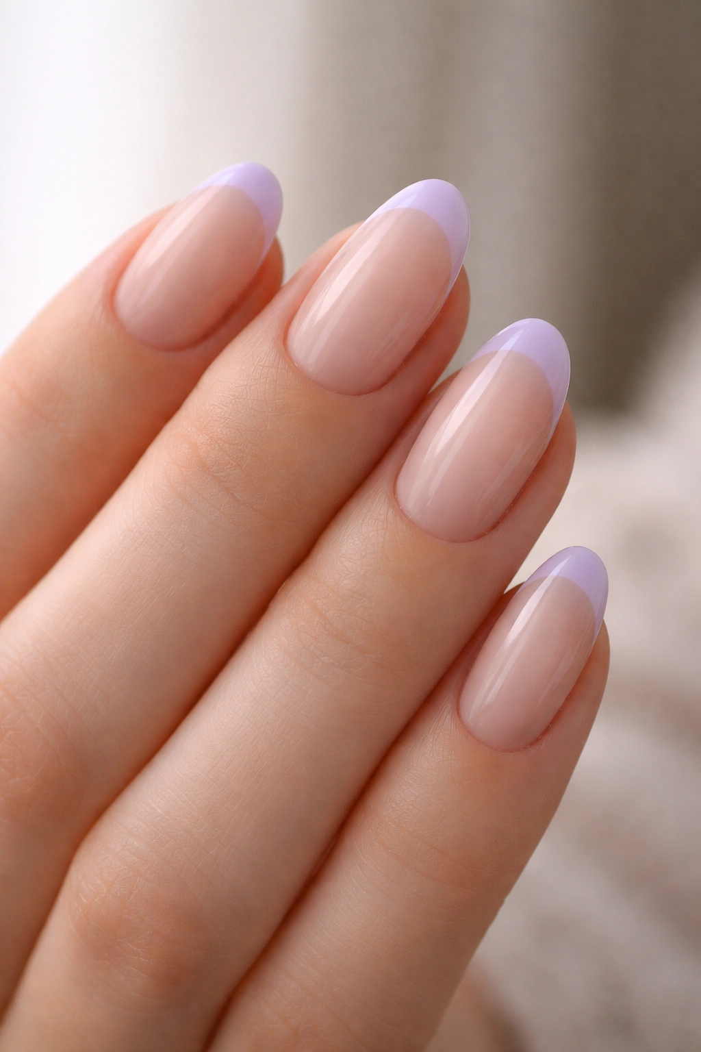Nails with sheer nude base and soft lavender tips on short almond nails