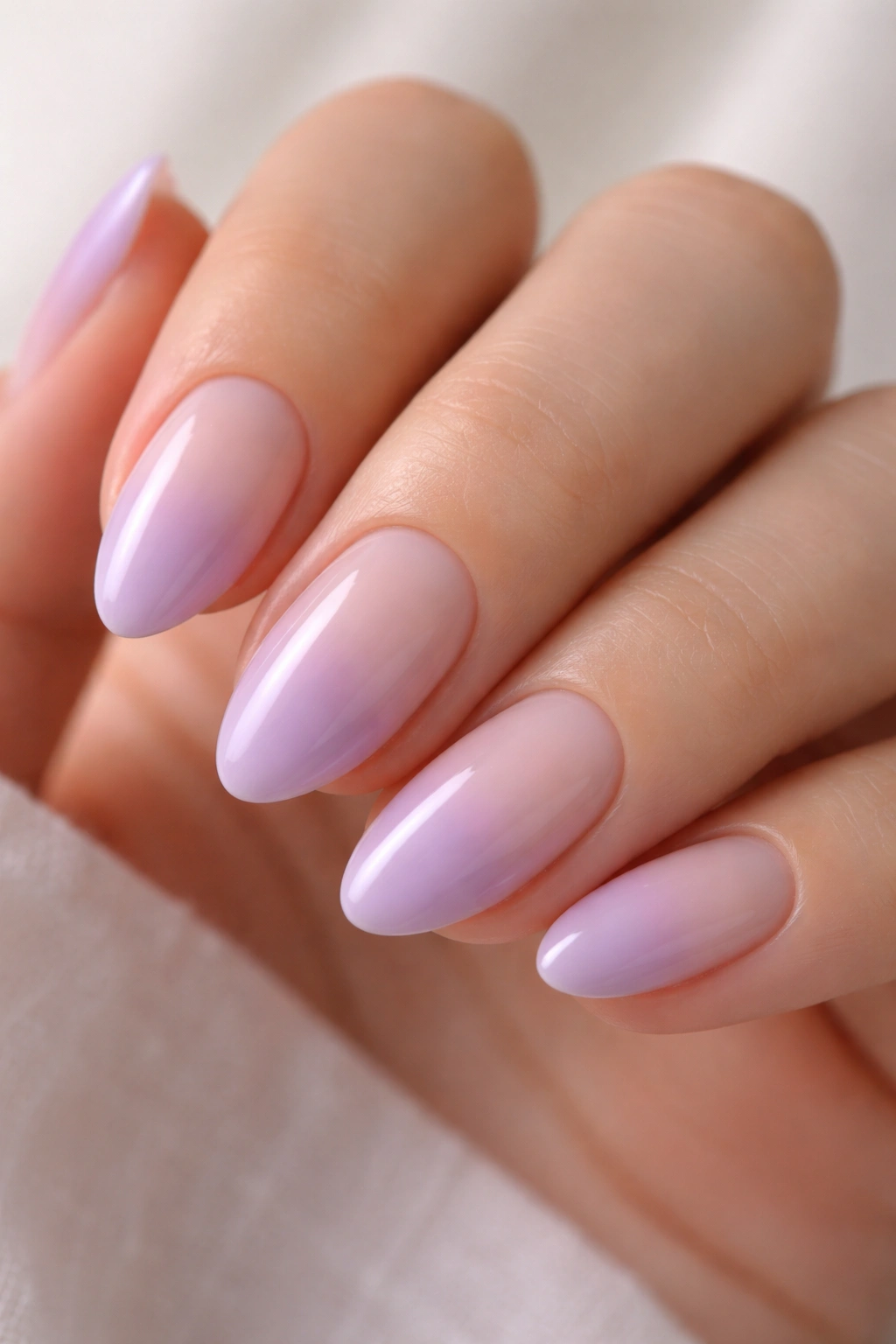 Close-up of short almond nails with lavender nude ombré gradient