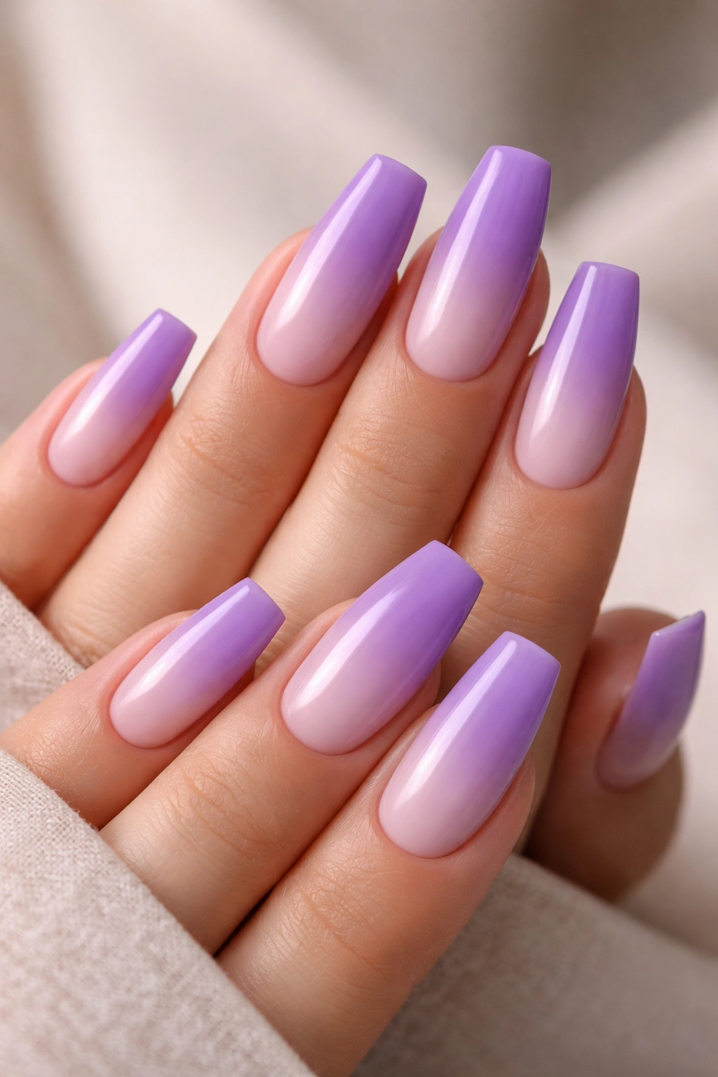Close-up of reverse-ombre lavender coffin nails from dark cuticle to pale tip