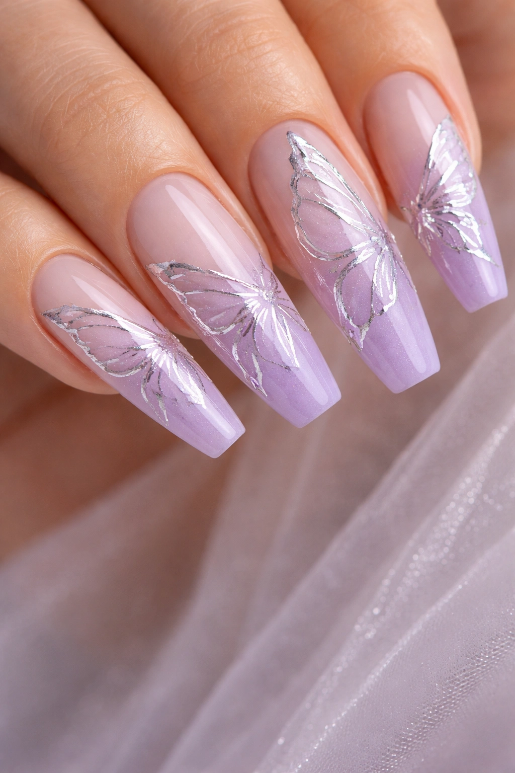 Lavender ombré nails with silver foil wing outlines on ballerina shape.