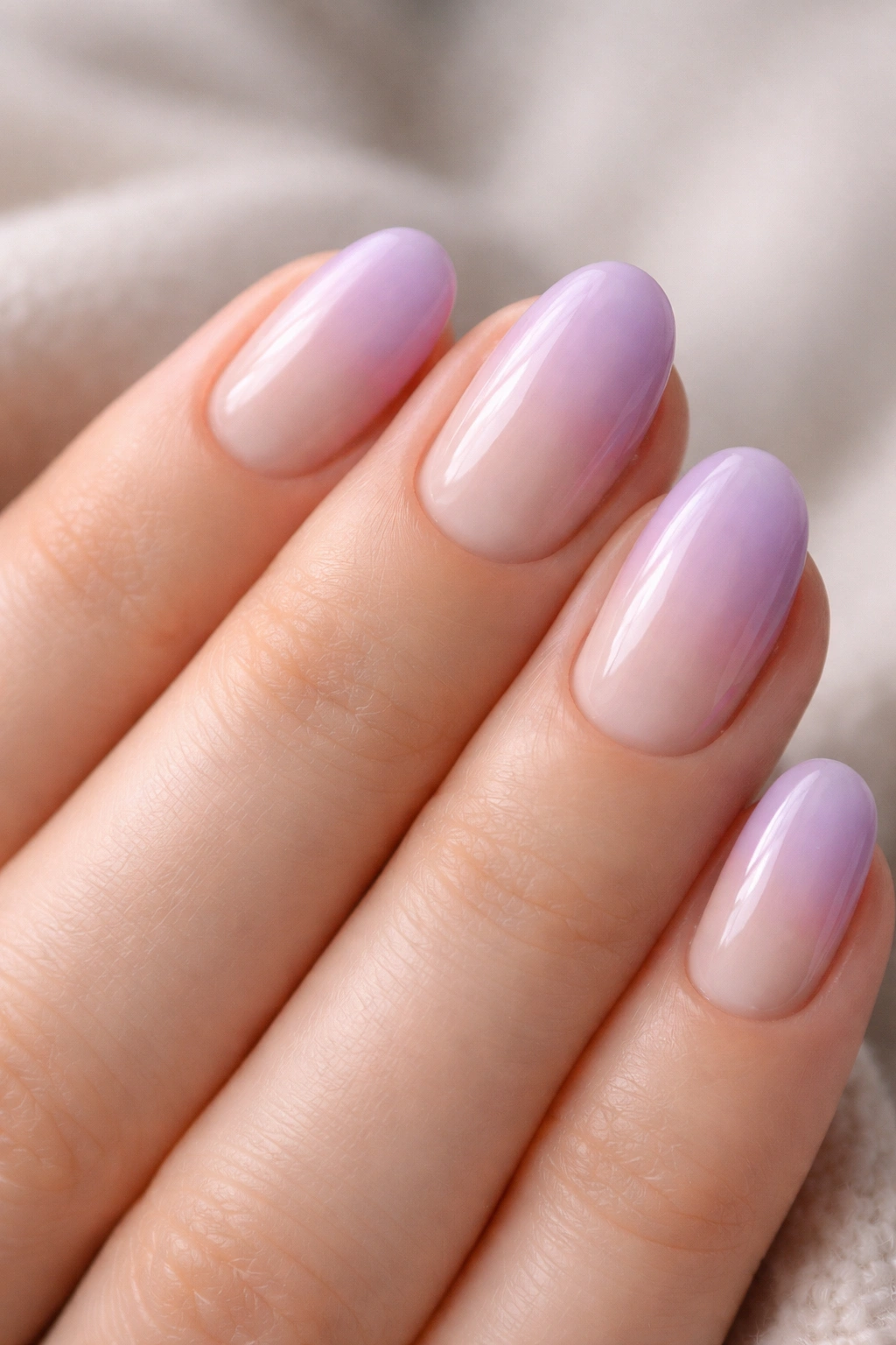 Close-up of short oval nails with nude-to-lilac ombré gradient