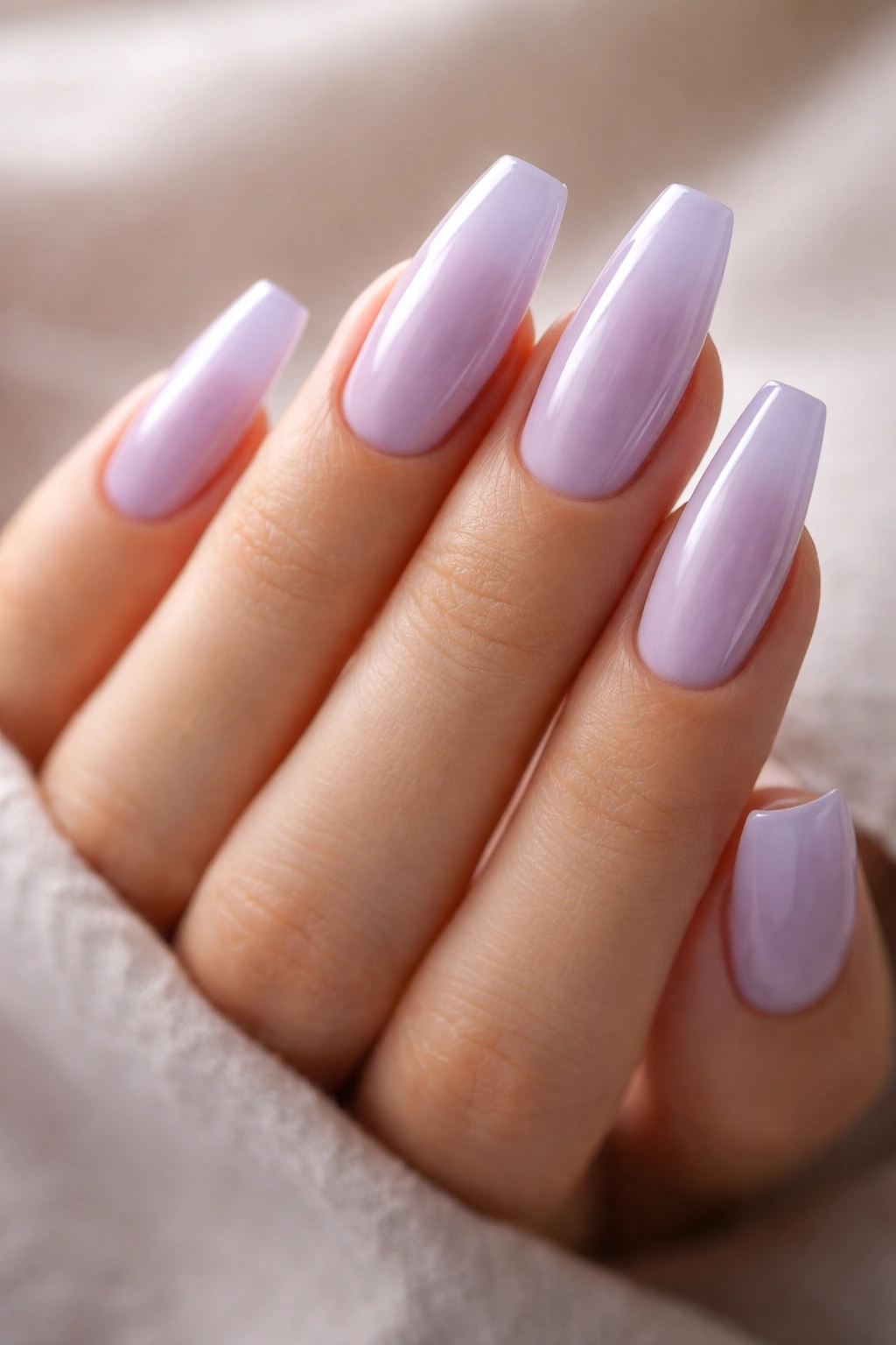 Close-up of medium coffin nails painted pastel lavender with translucent finish