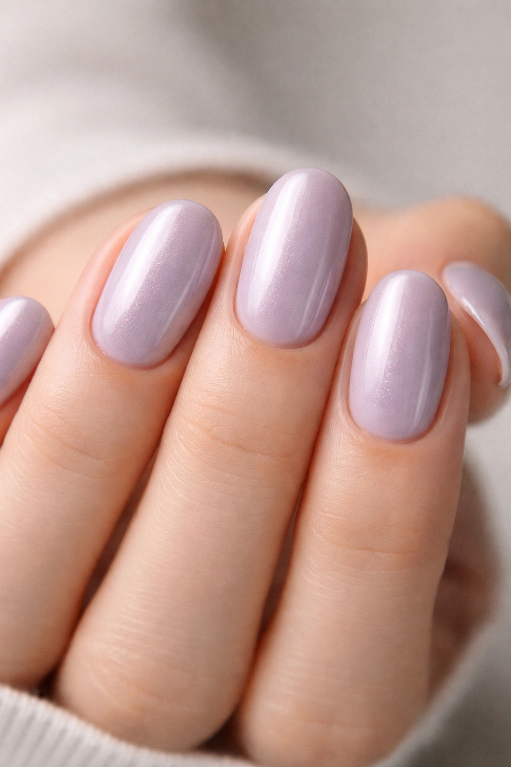 Close-up of soft lavender pearl nails on short oval nails with a milky sheen