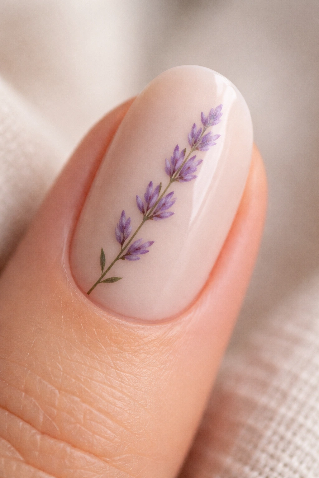 Close-up of a short oval nail with a lavender sprig design on a soft beige base