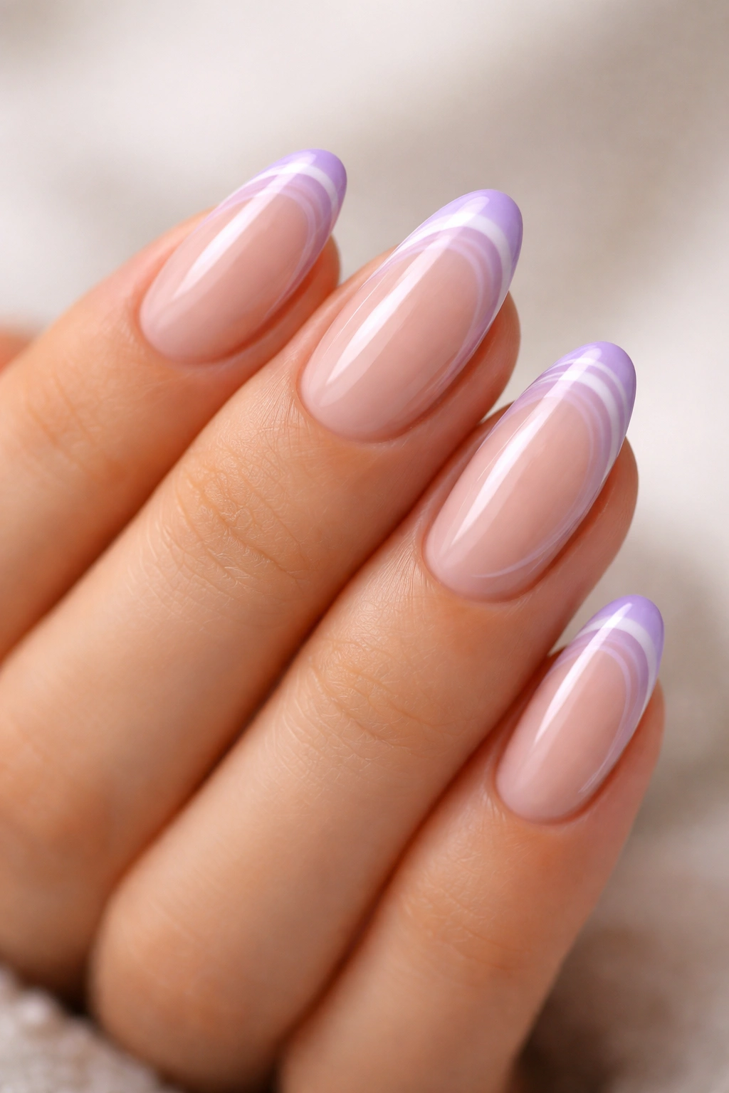 Close-up of short almond nails with lavender swirl near the tip on a nude base