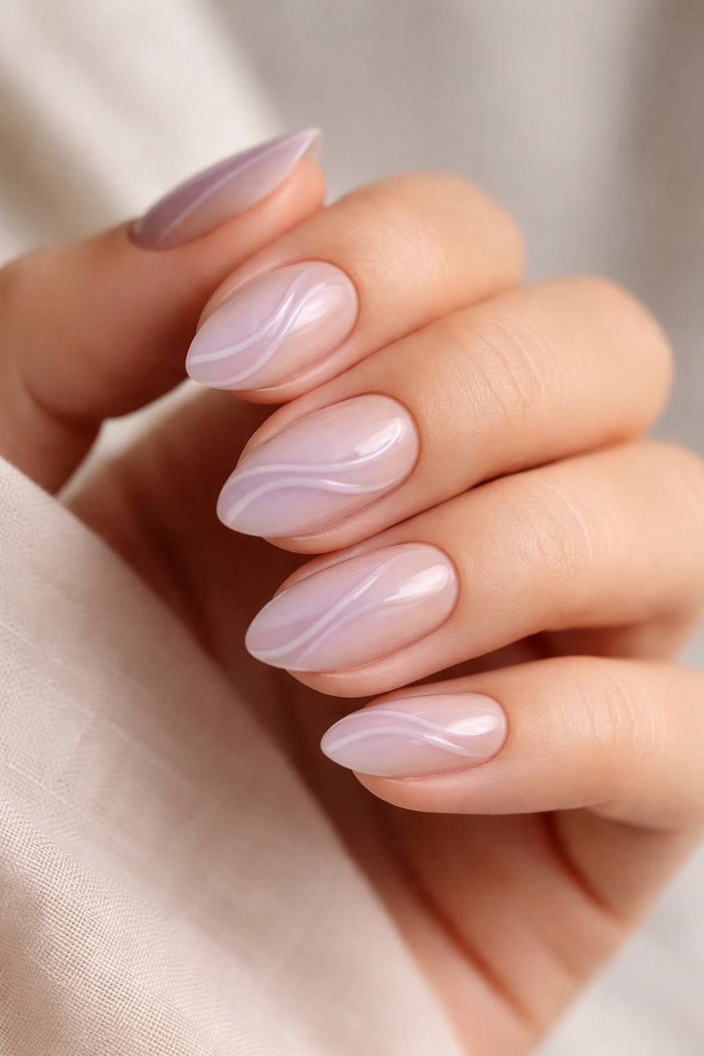 Close-up of lavender swirl nail art on nude base on short almond nails.