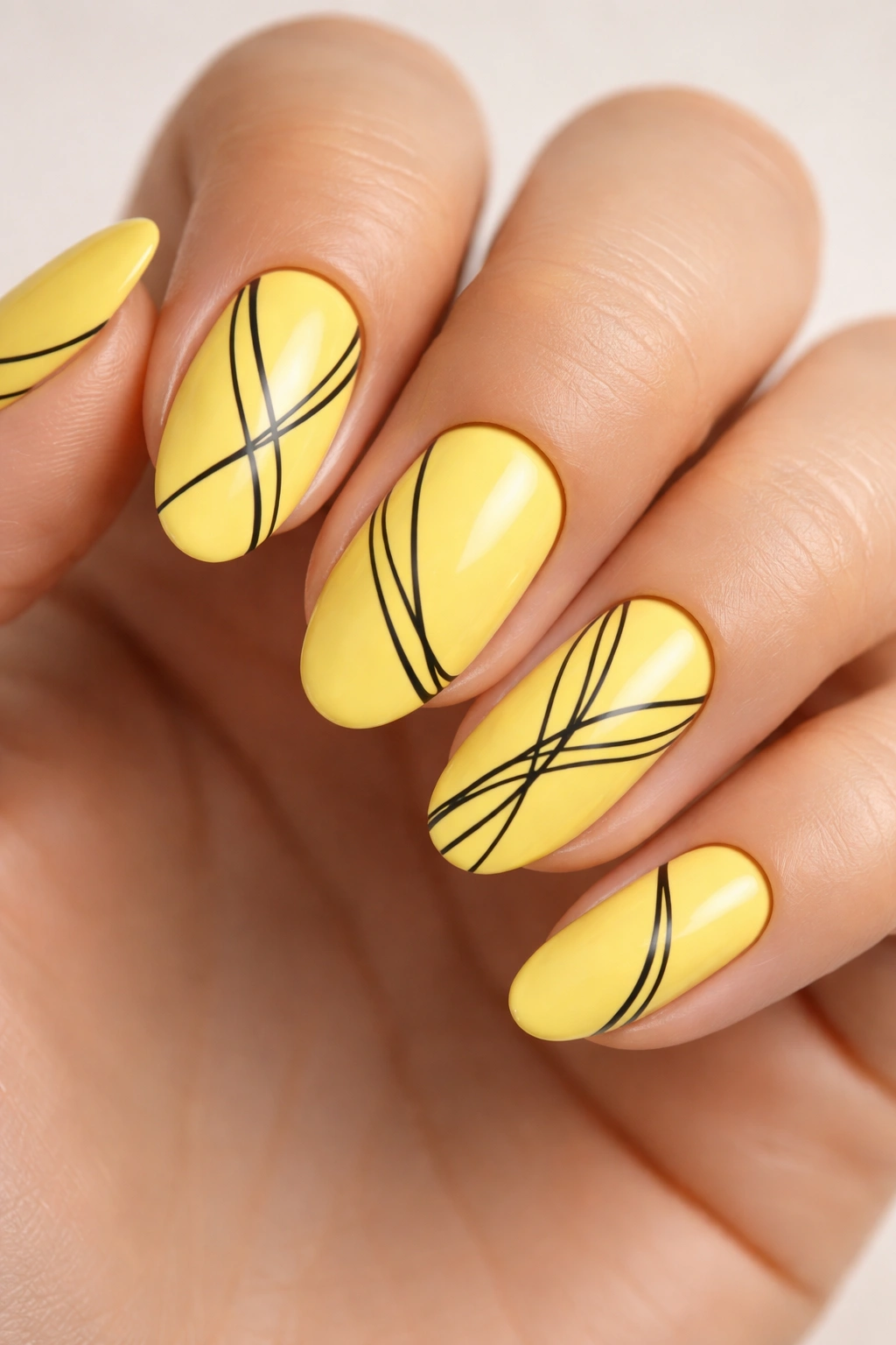 Close-up of oval nails with lemon yellow base and black line details