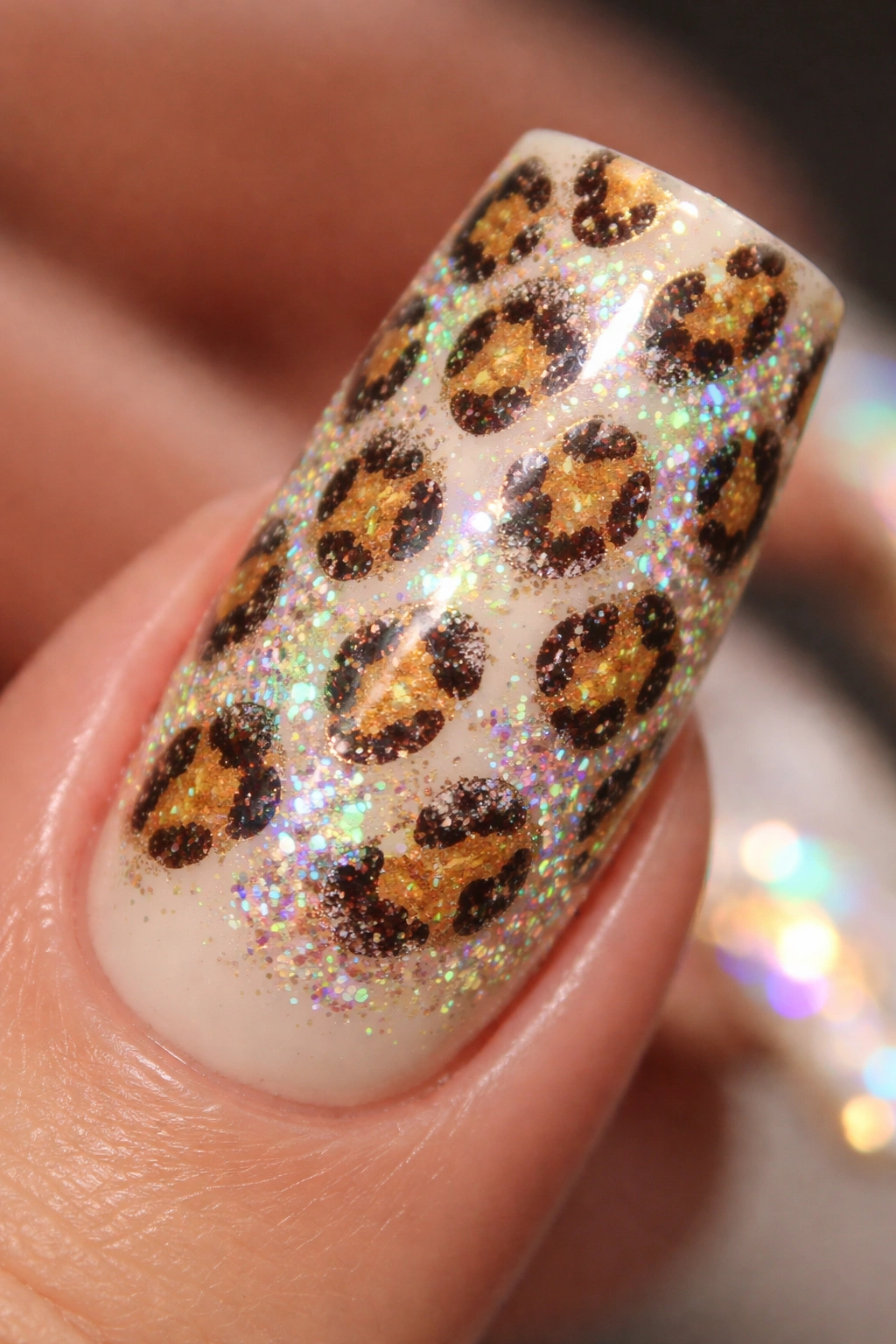 Close-up of a duck nail with leopard print and holographic shimmer on cream base