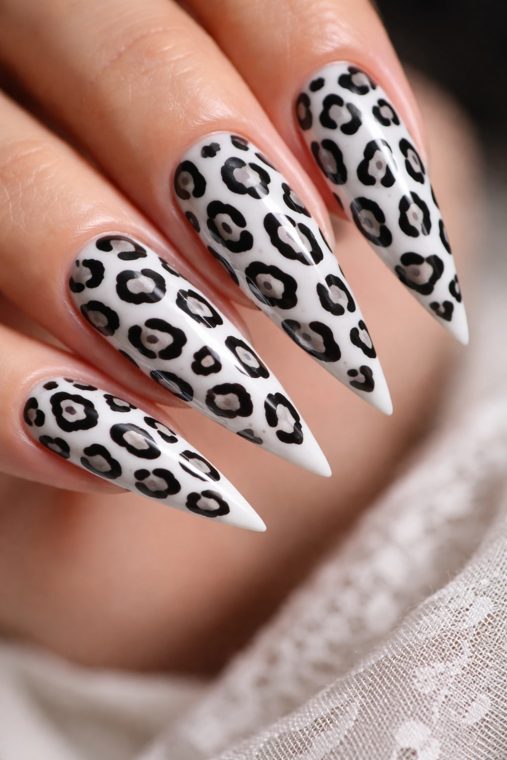Stiletto nails with black and white leopard print on white base