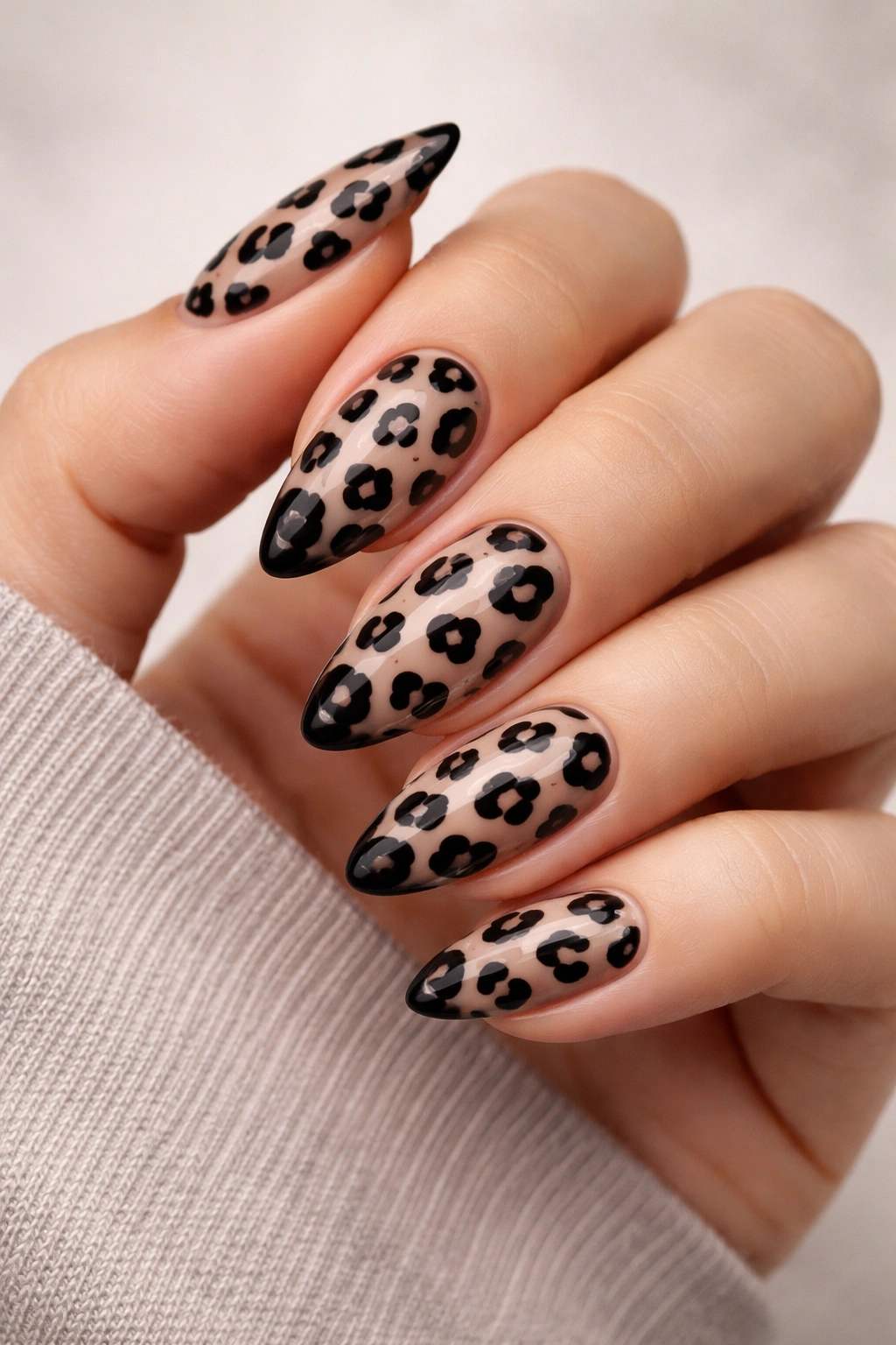 Close-up of black leopard print nails on a nude translucent base.