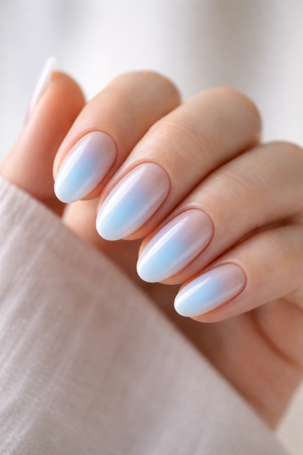 Short almond nails with soft centered glow diffused outward on a nude base.