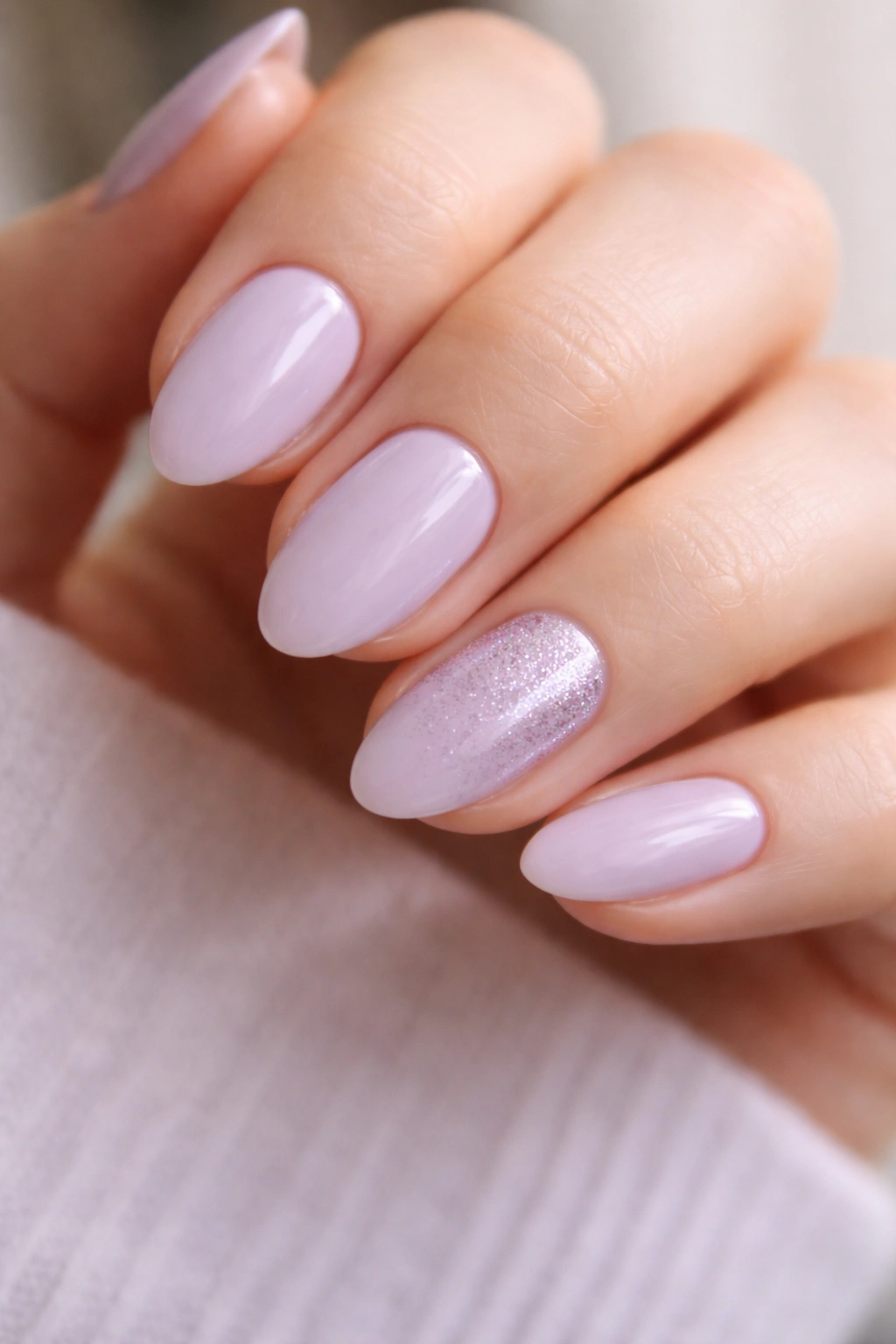 Close-up of short lilac nails with a fine glitter accent on one nail per hand