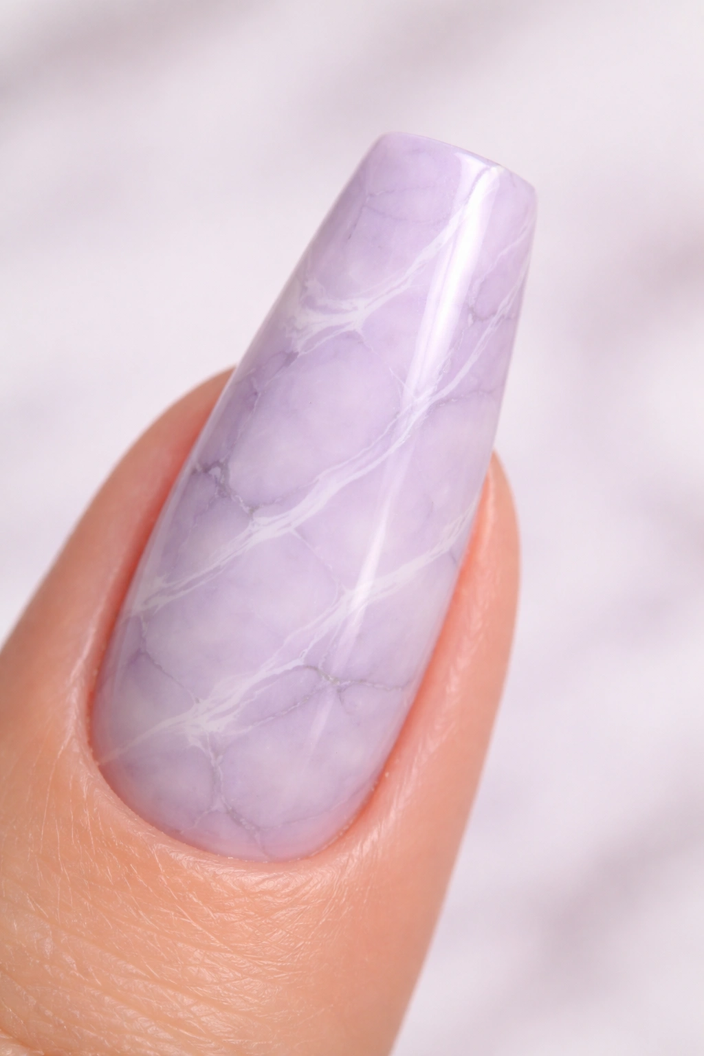 Close-up of a ballerina nail with pale lilac marble and thin white and gray veins