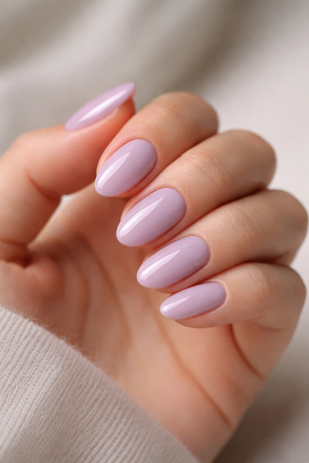 Close-up of short almond nails in soft lilac with a high-gloss finish