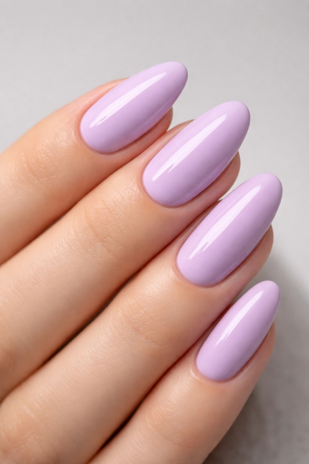 Close-up of lilac nails with a glossy pastel manicure on a neutral gray background